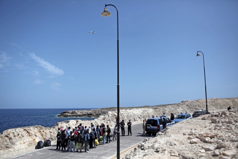  Lampedusa, Italie, le 12 avril 2011.
Procédure d'évacuation massive de migrants en provenance d'afrique du nord a été effectuée par la police italienne sur la petite île de Lampedusa, située au large de la Sicile et proche des côtes africaines. Ici, les migrants sont fouillés avant de monter dans un bateau(L'Excelsior)qui les transfèrent vers Catane en Sicile. L'avion passant au dessus de ce groupe de personnes ramène des migrants tunisiens qui ont été embarqués de force quelques instants avant à l'aéroport de Lampedusa. Environ 850 personnes ont été évacuées aujourd'hui, par voie maritime et aérieenne.
©Pierre Albouy