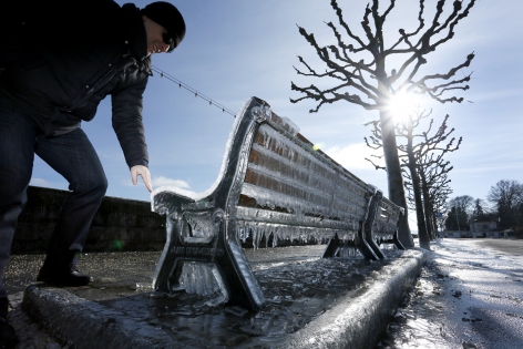  A man touches the ice of a frozen public bench next to the lake side due to the heavy wind conditions in Versoix near Geneva, February 8, 2015. REUTERS/Pierre Albouy (SWITZERLAND)